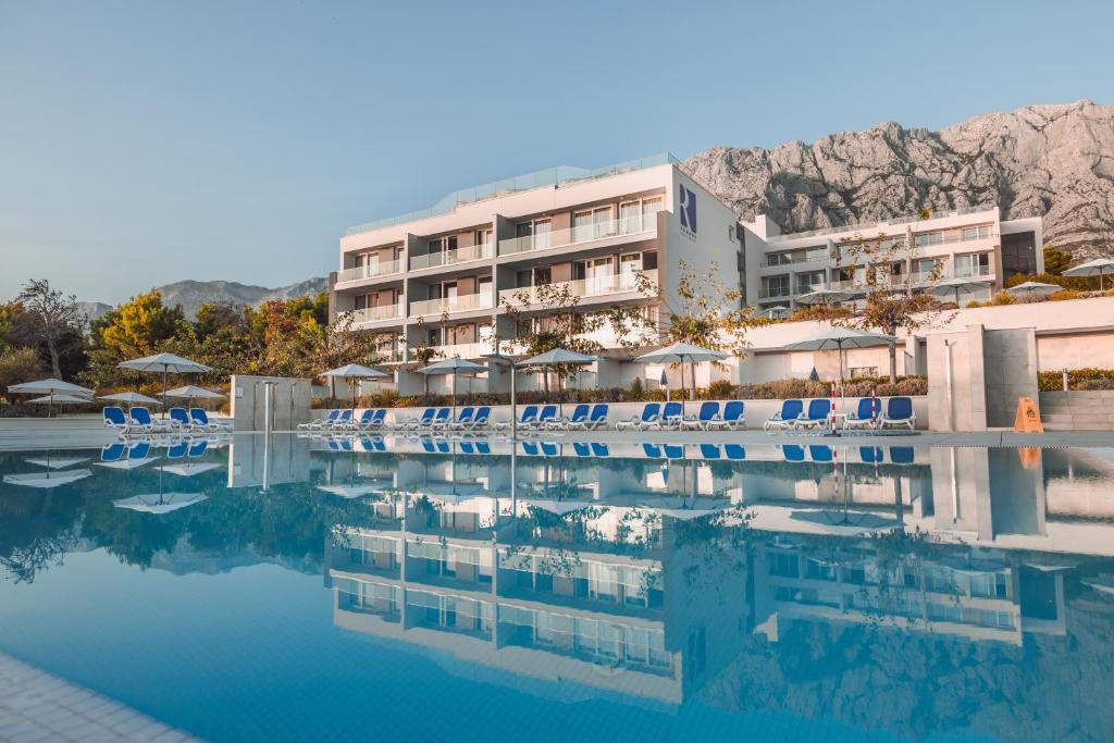 a swimming pool with chairs and a hotel at Romana Beach Resort in Makarska