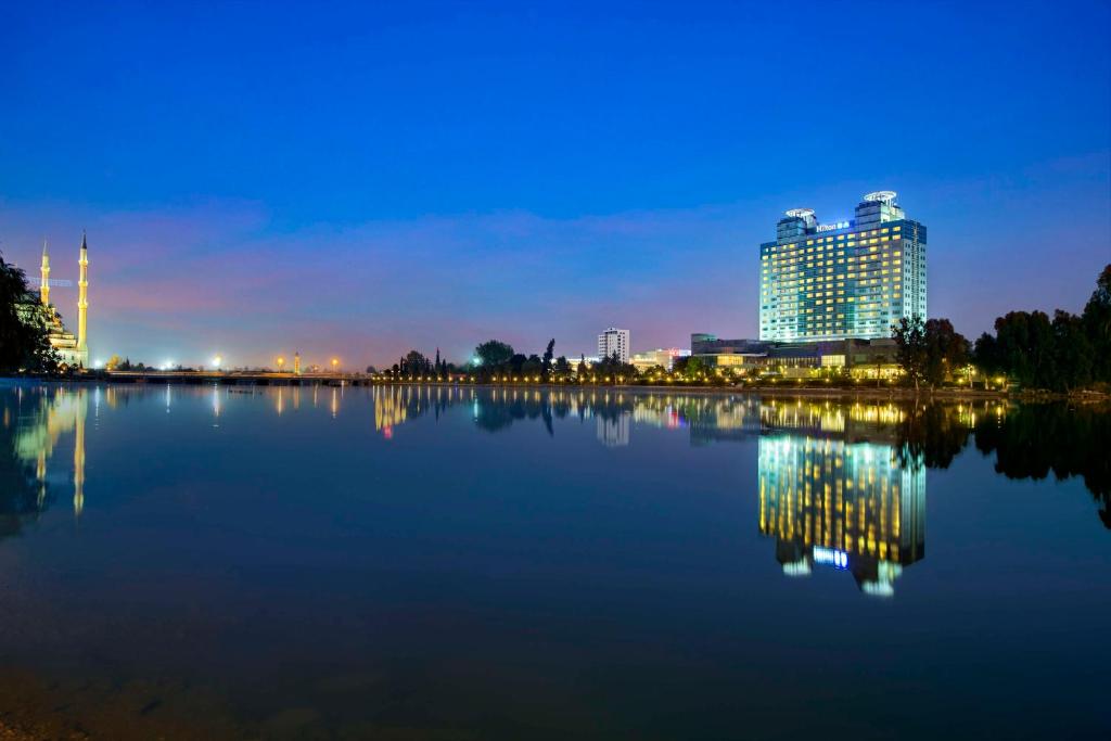 ein großer Wasserkörper mit Gebäuden im Hintergrund in der Unterkunft Adana HiltonSA Hotel in Adana