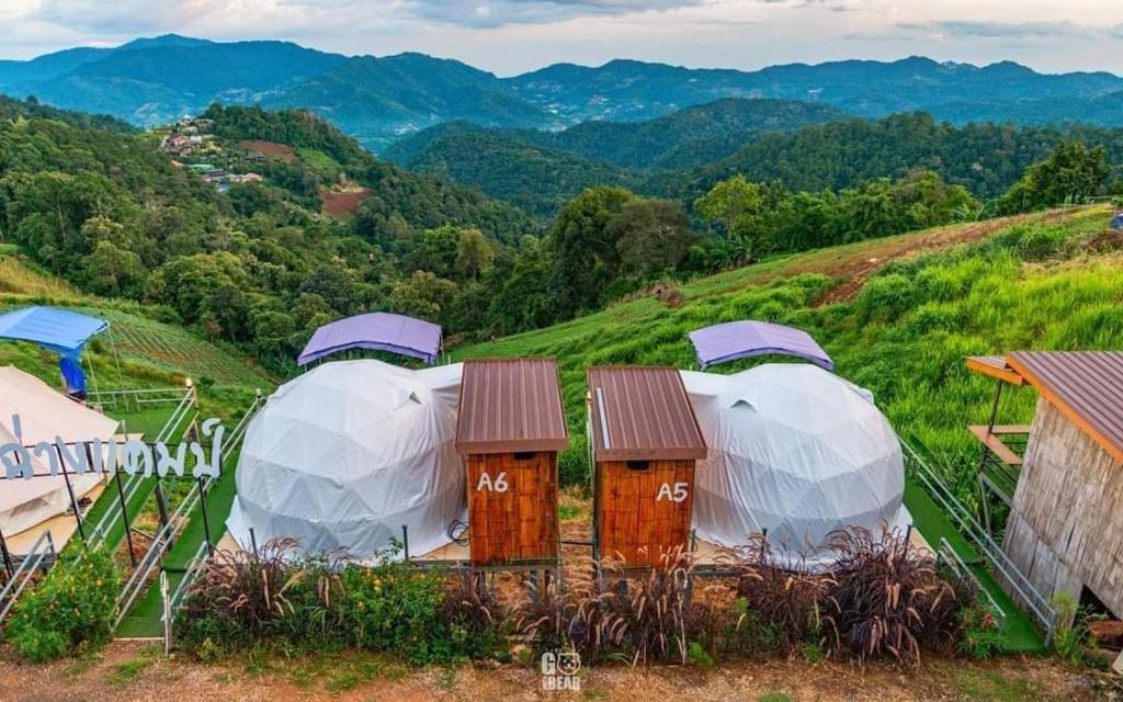 um grupo de cúpulas no topo de uma colina em อาฉ่างแคมป์ Achang Camp em Mon Jam