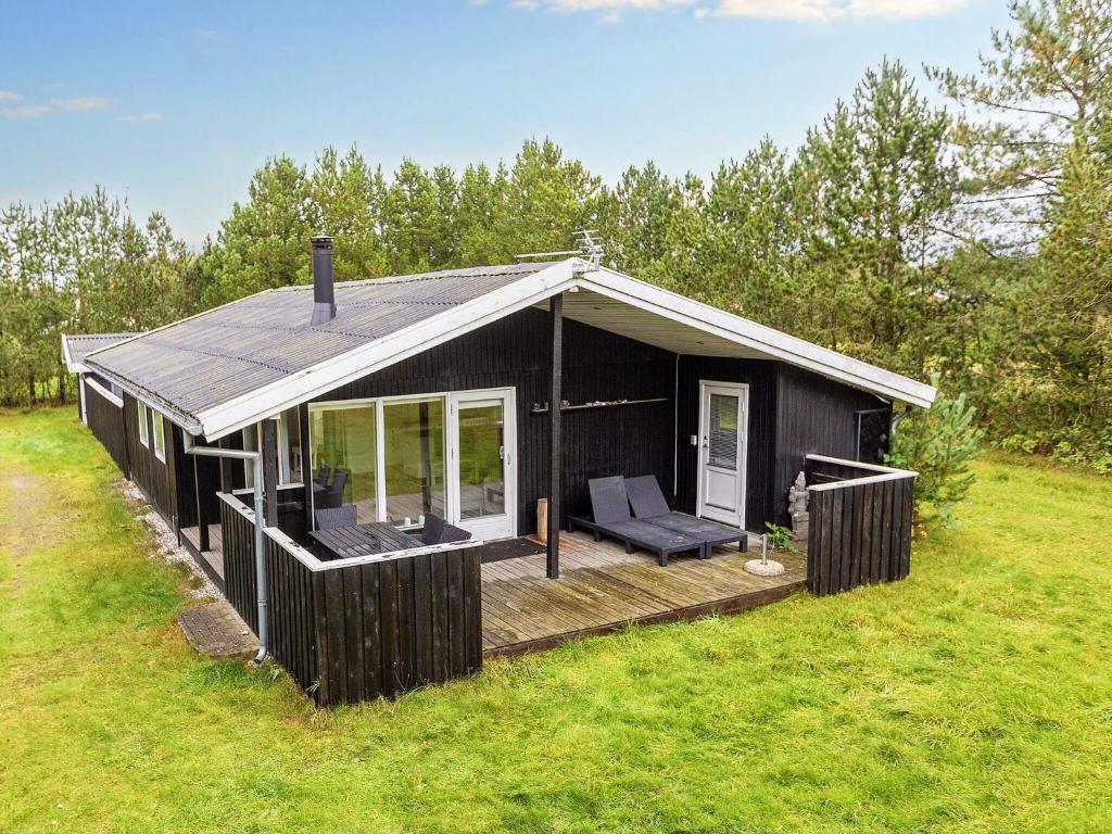 a black cabin with a deck in a field at 6 person holiday home in Hals-By Traum in Hals