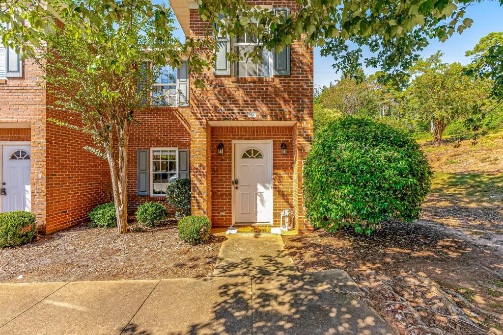 a brick house with a white door and a tree at Tranquil Townhome in Auburn