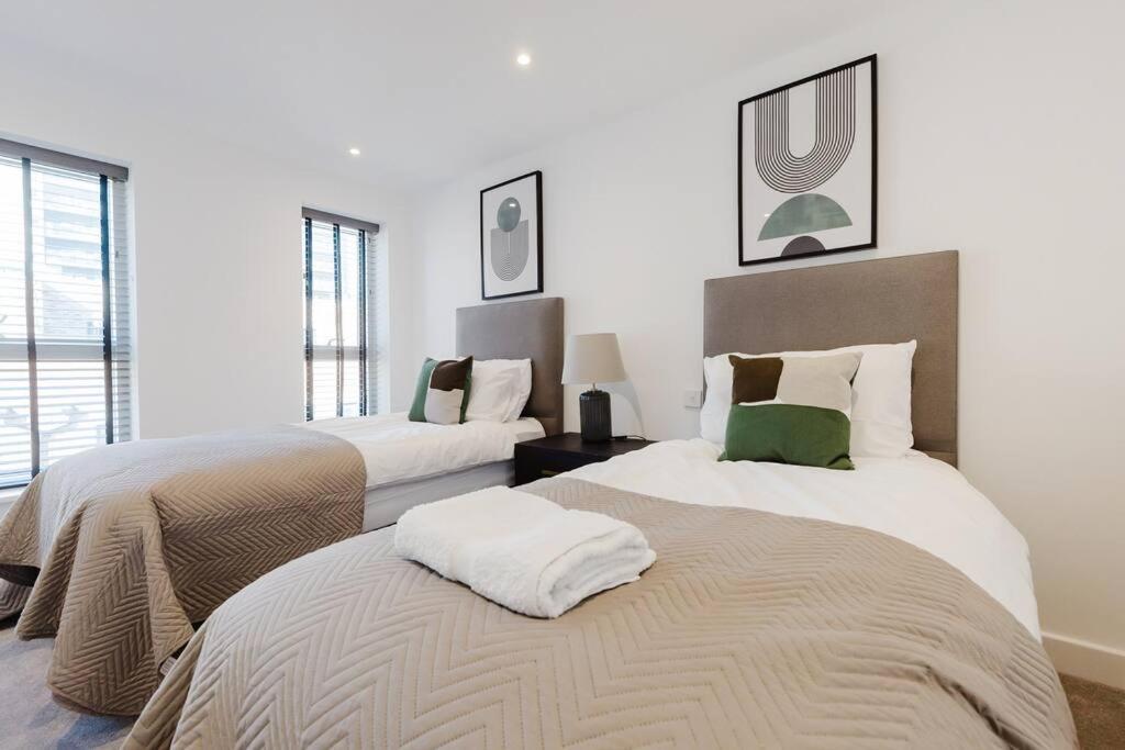 two beds in a room with white walls and windows at 4-Level Luxury 2 Bedroom House Sleeps 6, Rooftop, Harry P & Free Parking in Watford