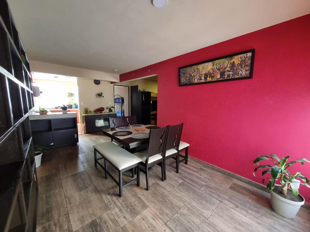 une salle à manger avec un mur rouge, une table et des chaises dans l'établissement Bonito departamento familiar, à Mexico