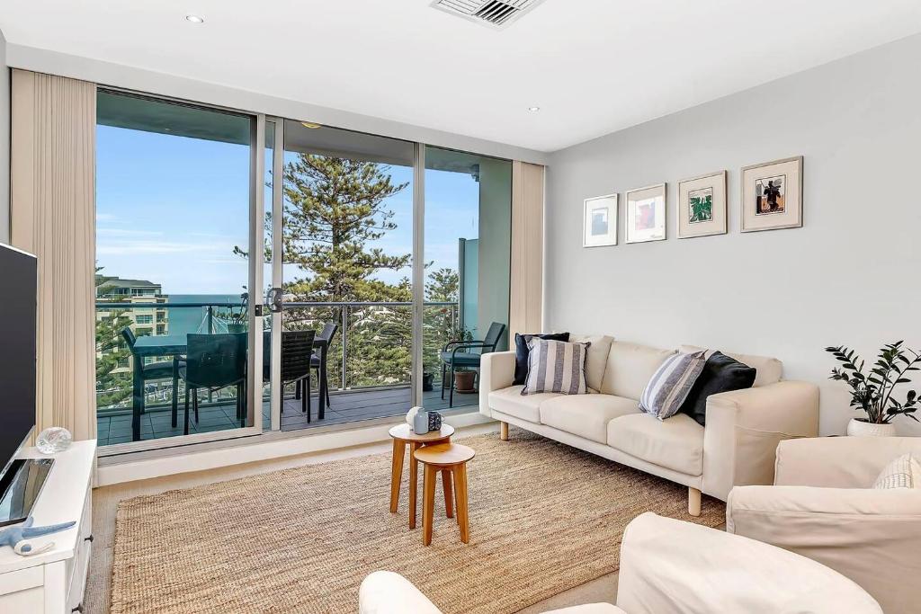 uma sala de estar com um sofá e vista para o oceano em Waterfront Resort-Style Living at Glenelg Beach em Glenelg