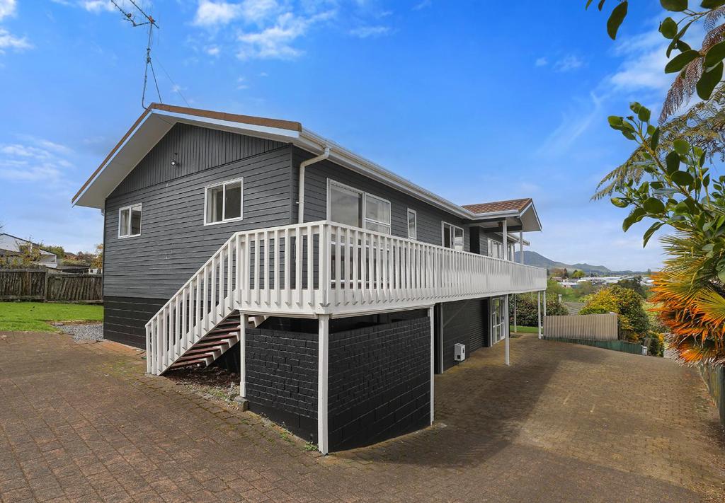 ein schwarzes Haus mit einer weißen Terrasse und einer Treppe in der Unterkunft Woodward House Taupo in Taupo