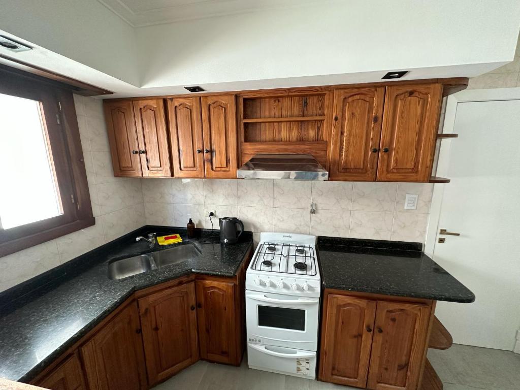 cocina con armarios de madera y horno de fogón blanco en Mar y Cielo en Necochea