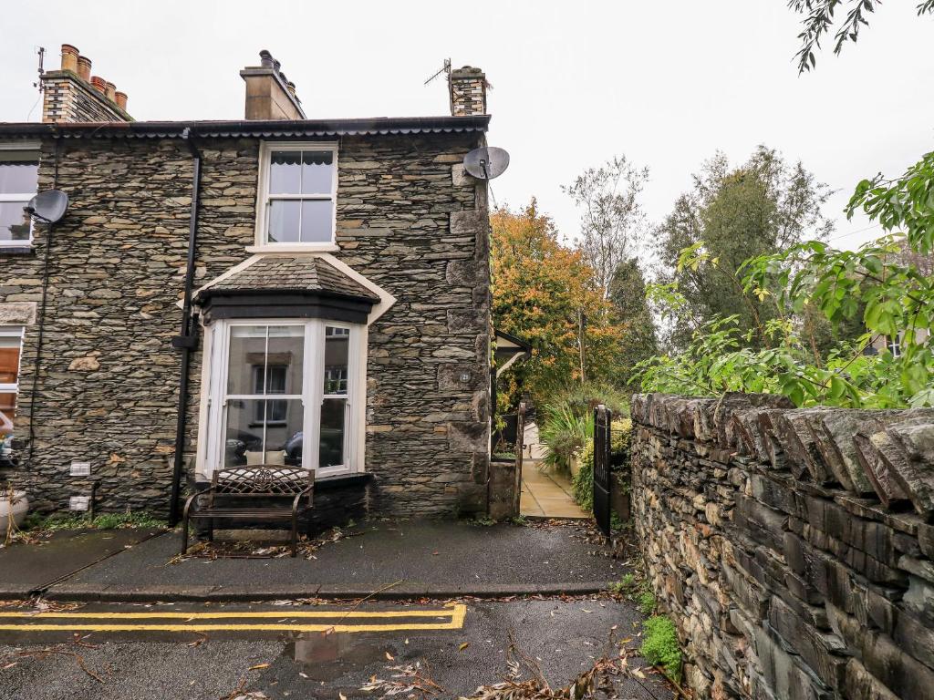 an old stone house with a window and a stone wall at Walkers Rest in Windermere