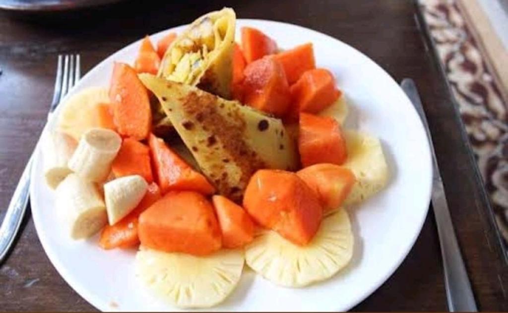 um prato branco de alimentos com frutas sobre uma mesa em Gubuk Baru Homestay em Tetebatu