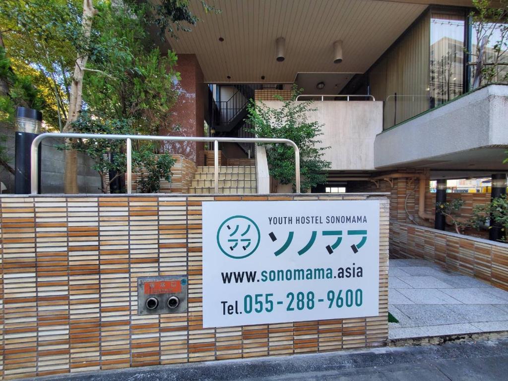 a sign for a building in front of a building at ユースホステルソノママ in Kofu