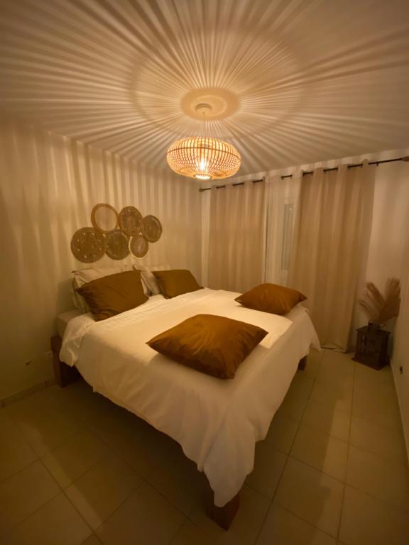 een slaapkamer met een groot wit bed en een kroonluchter bij Monvert Evazion in Le Robert