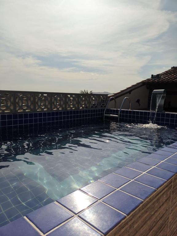 una piscina con azulejos azules en el lateral de una casa en Região dos Lagos - casa para temporada en São Pedro da Aldeia