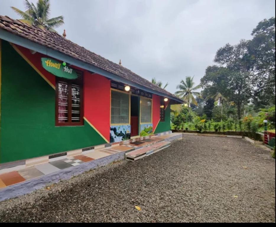 un edificio con una fachada verde y roja con una acera en Honey hut. en Anachal