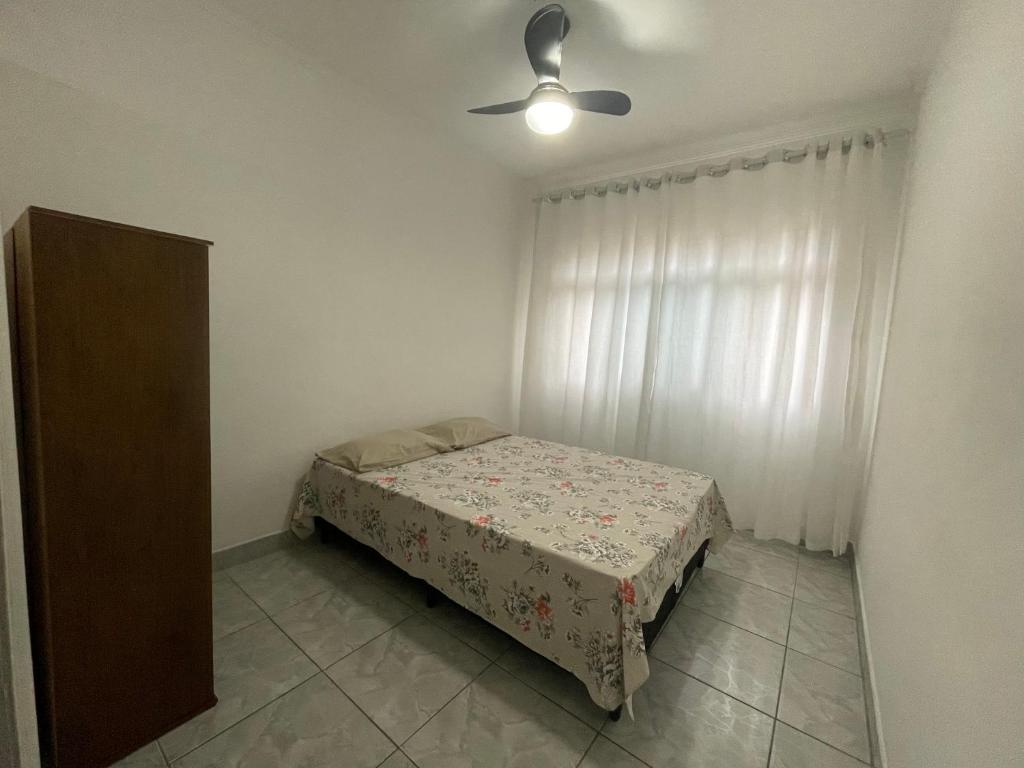 um quarto com uma cama e uma ventoinha de tecto em Kitnet perto da praia na Praia Grande