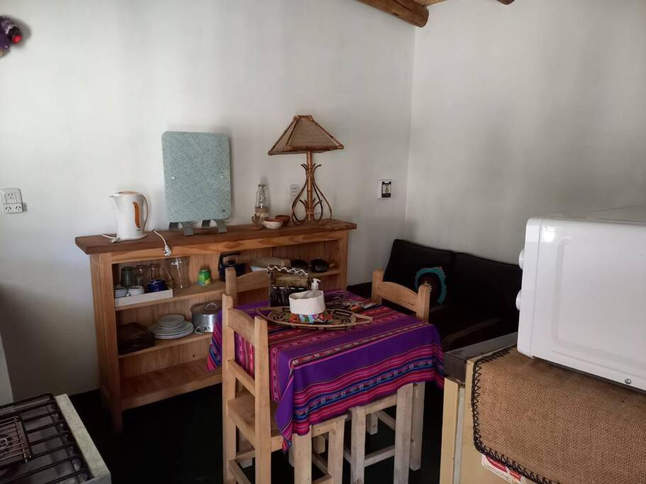 a living room with a table and chairs and a microwave at Cabaña La Apacheta Cachi Salta in Cachí