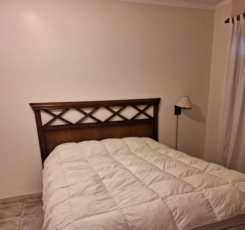 a bedroom with a white bed with a wooden headboard at Céntrico y confortable in Paraná