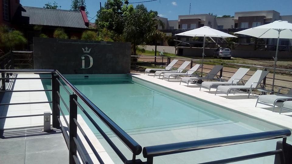 uma piscina com espreguiçadeiras e guarda-sóis em DINASTIE APART HOTEL em Chajarí