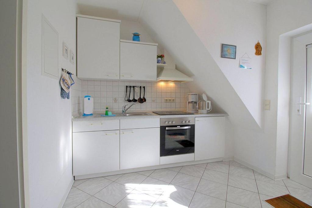 uma cozinha com armários brancos e um fogão em KI22-15 Haus Seeadler em Dorum Neufeld