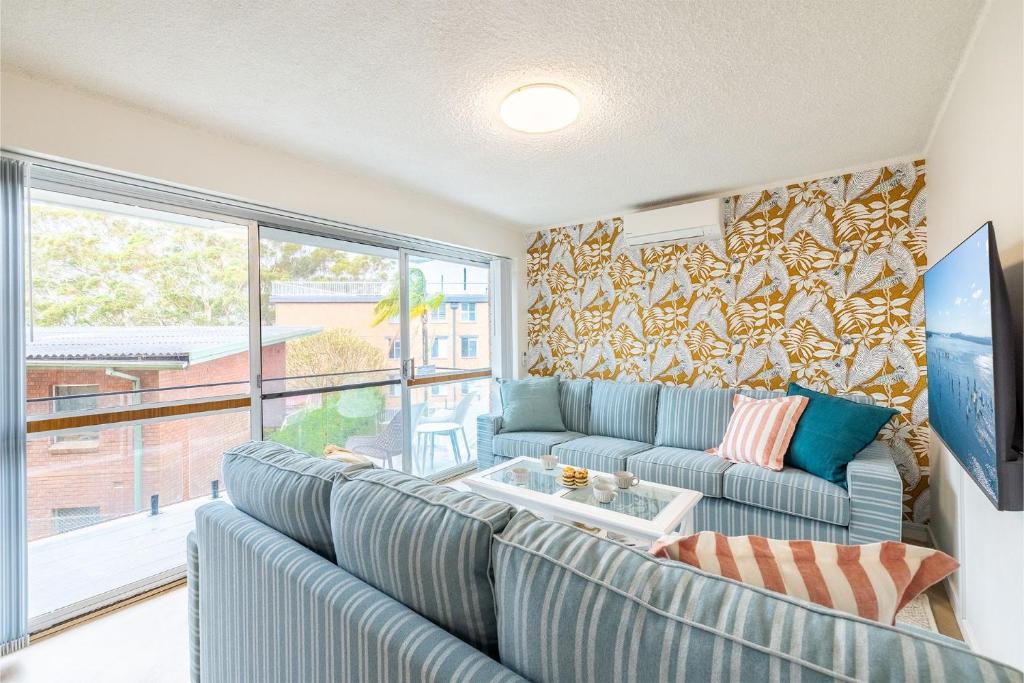 a living room with blue couches and a large window at Thurlow Lodge, 7,6 Thurlow Avenue - Beautifully styled unit with WiFi, views and a pool in Nelson Bay