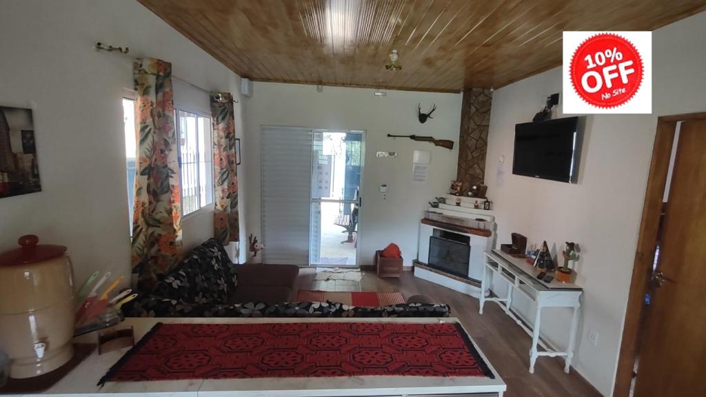 uma sala de estar com um sofá e uma televisão em Casa de Campo Refúgio Jaguary em Monte Verde