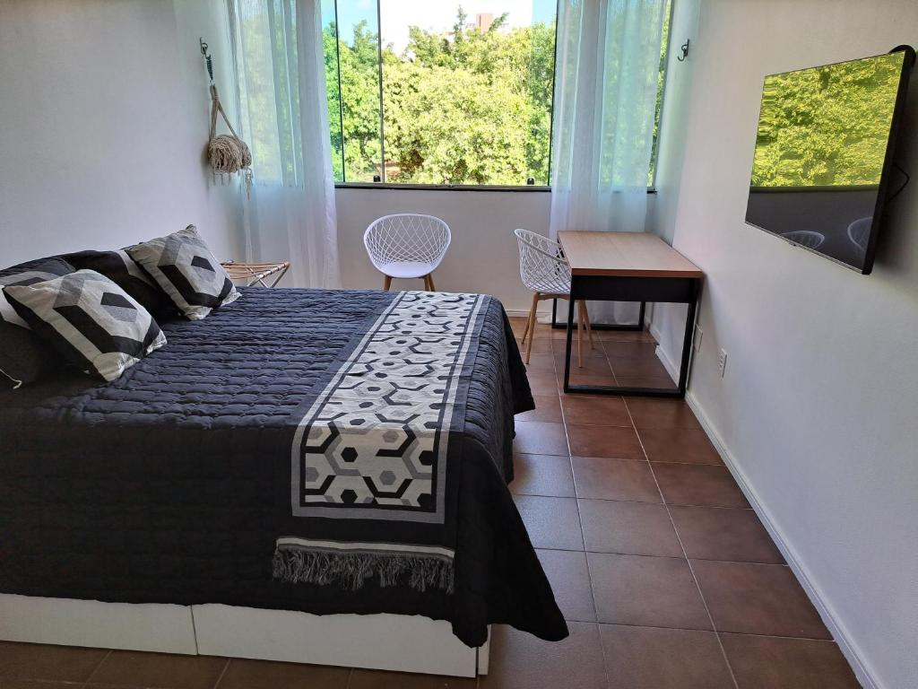 a bedroom with a bed and a desk and a window at Studio 109-comfortable, practical, great location in Brasilia