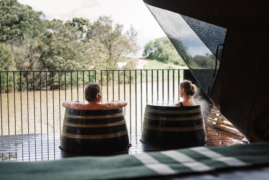 Un uomo e una donna seduti in barili in acqua di Metung Hot Springs a Metung