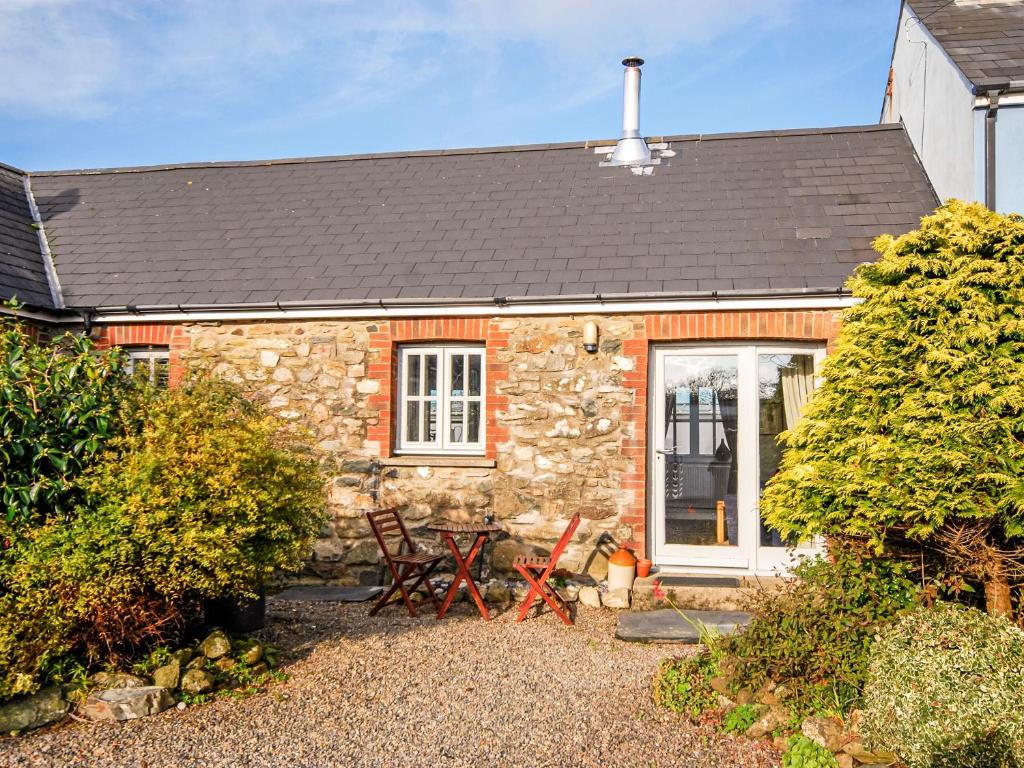 a stone cottage with two chairs in front of it at Llys Bychan in Granston