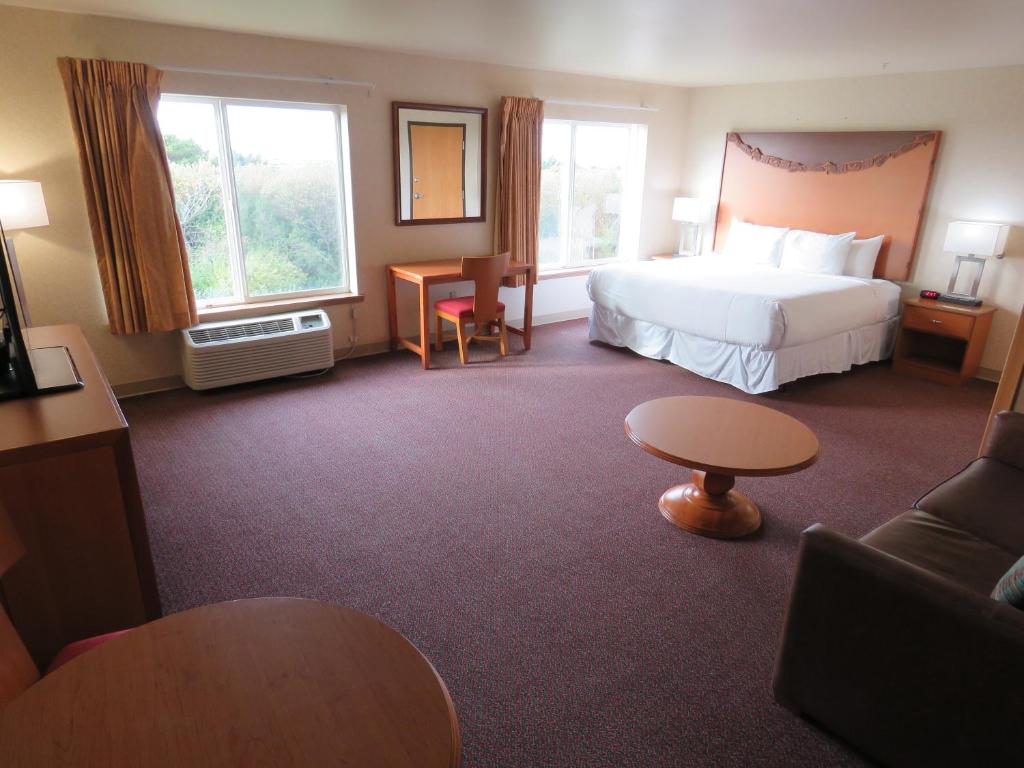 Pacific Sunrise Inn & Suites في أوشن شورز: غرفه فندقيه بسرير واريكه