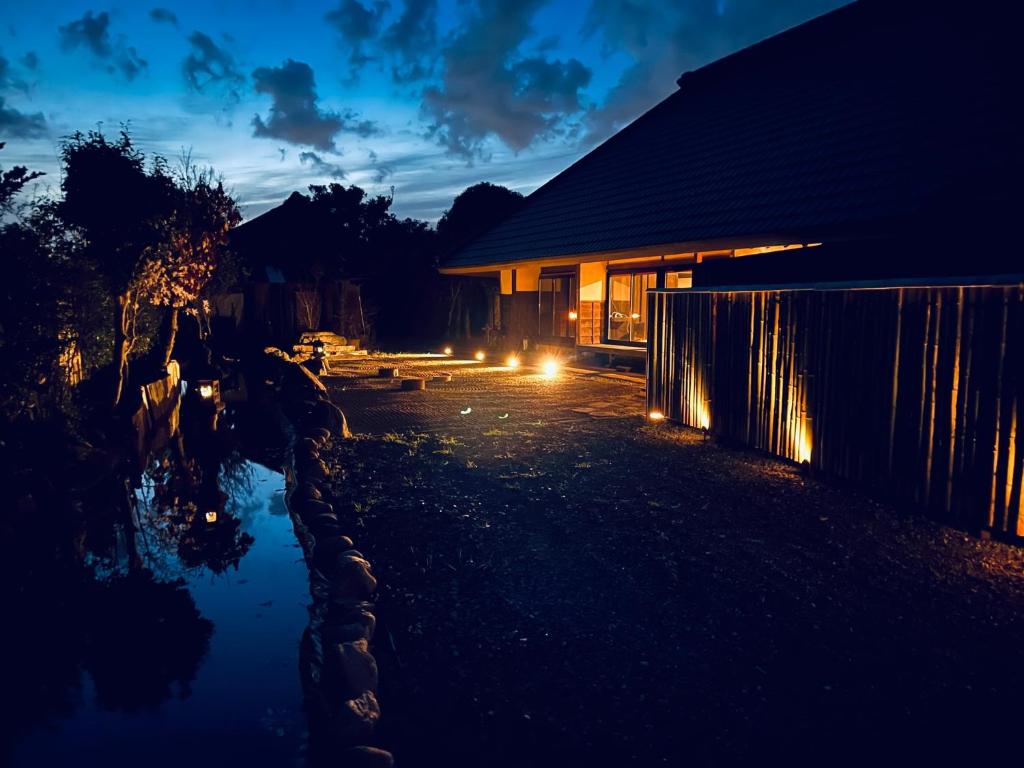 uma casa iluminada à noite com um lago em GOEMON The Last Japan 
