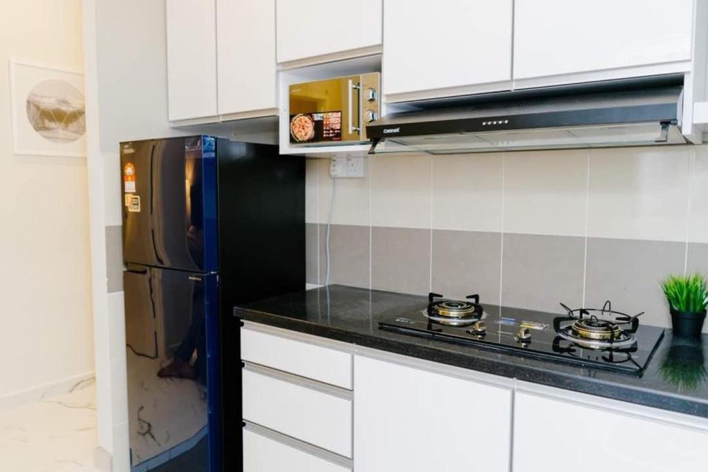 a kitchen with a black stove and a refrigerator at Mimpi D View Homestay in Kuala Terengganu