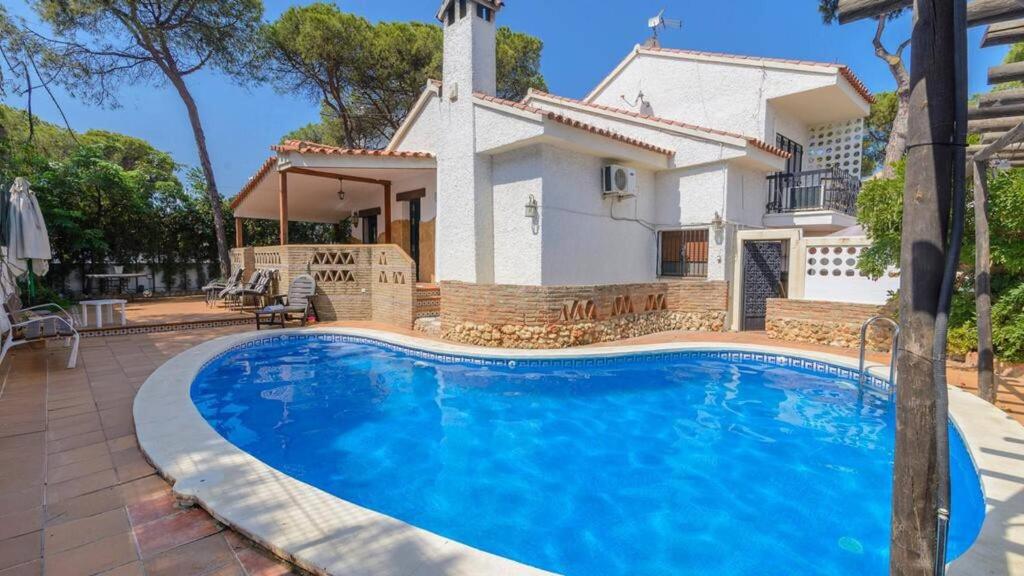 a villa with a swimming pool in front of a house at Marquise House con piscina privada in Punta Umbría