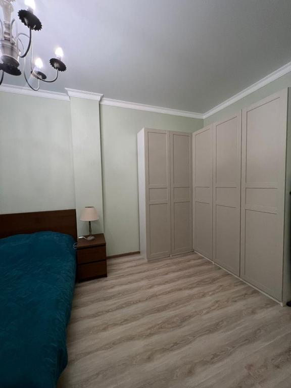 um quarto com paredes brancas e uma cama e um candeeiro em Квартира em Taldykolʼ