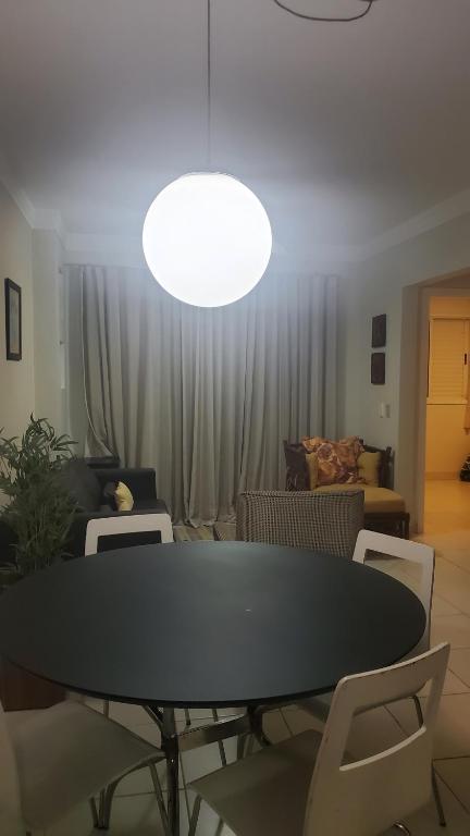 a table and chairs in a living room with a light at Guarujá - Praia do Tombo - Apartamento in Guarujá