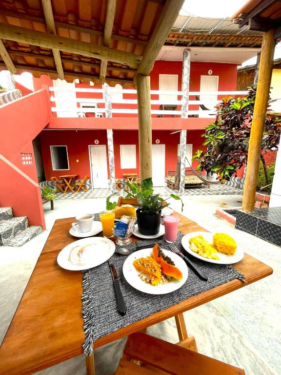 a wooden table with plates of breakfast food on it at Hospedaria Mucugê - na principal rua da cidade, Rua do Mucugê - Arraial d'Ajuda in Arraial d'Ajuda