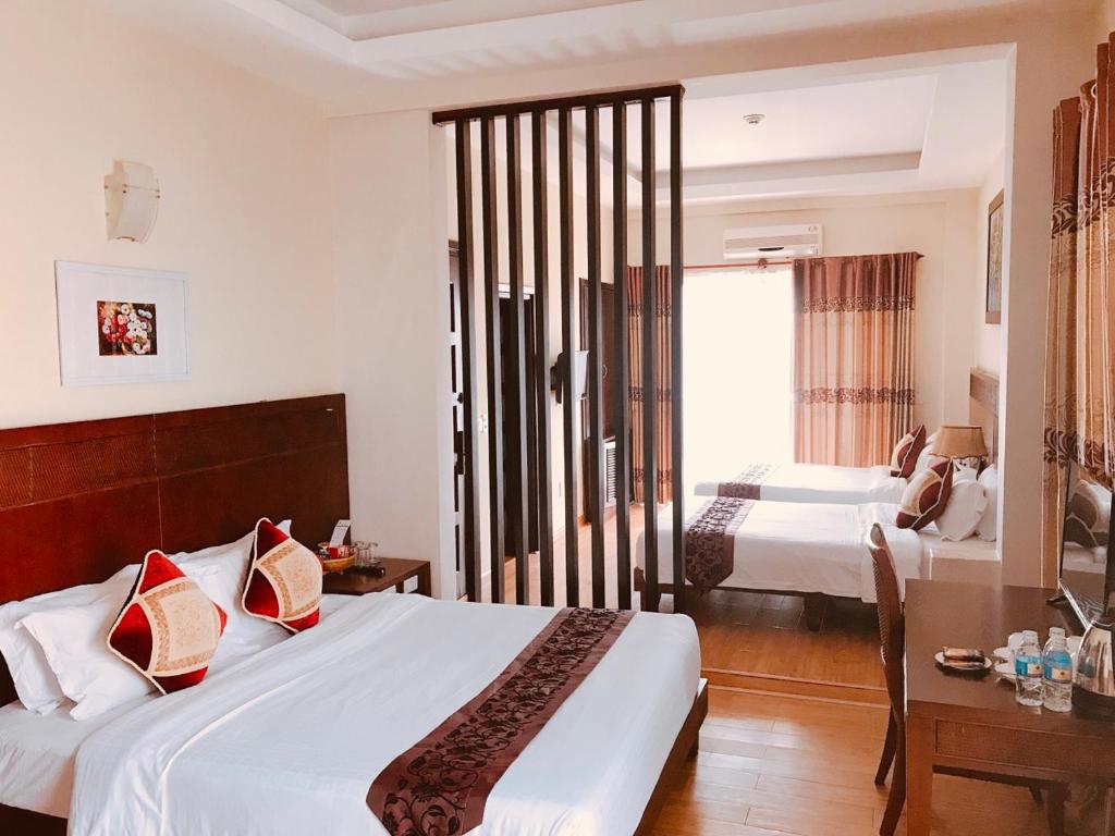 a hotel room with two beds and a window at Little Gold Hue boutique hotel in Hue