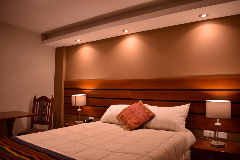 a bedroom with a large bed with a wooden headboard at Artezana Hotel in Cusco