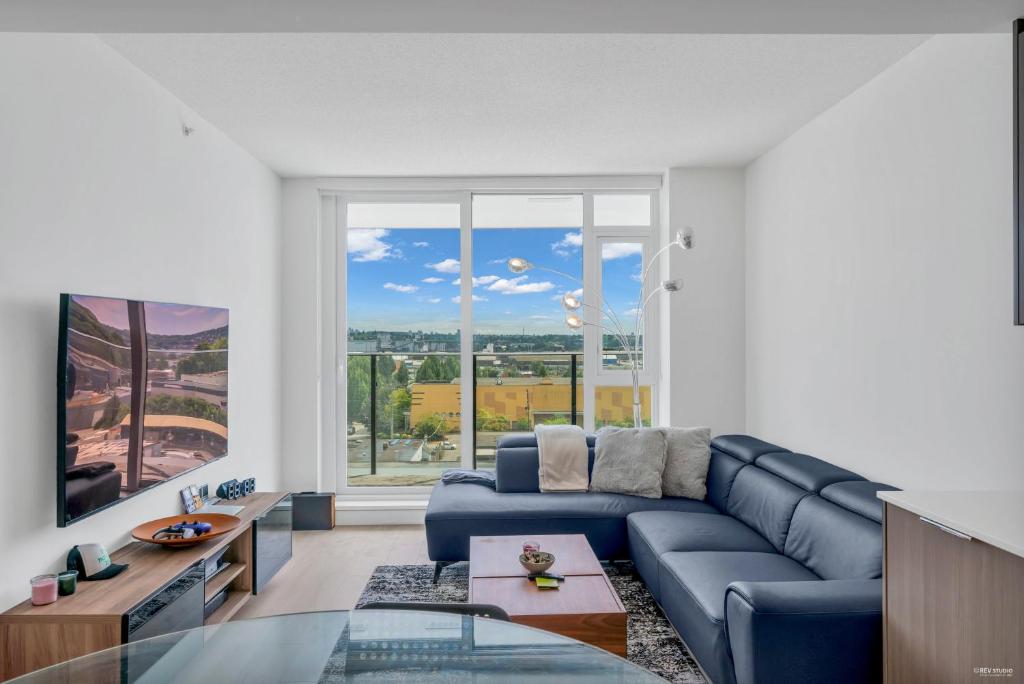 sala de estar con sofá azul y ventana grande en Kind One Bedroom Apartment en North Vancouver