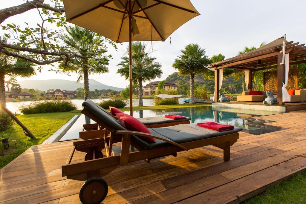 una silla con sombrilla en una terraza junto a la piscina en Dasiri Lakefront Villa, en Hua Hin
