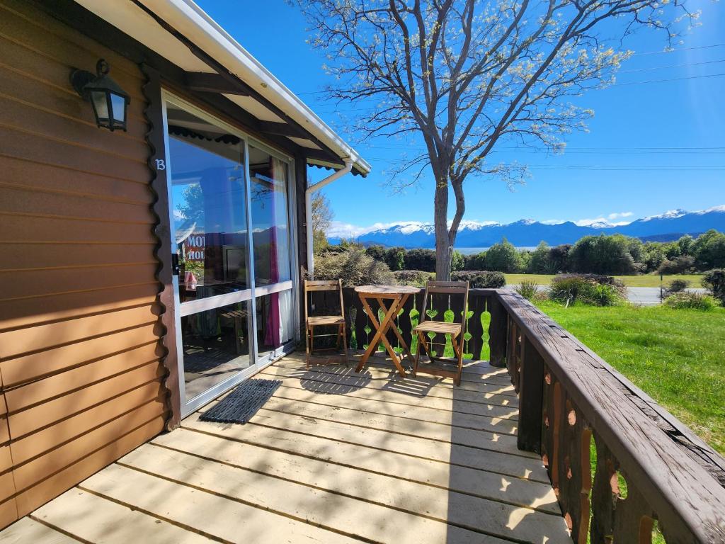 a deck with a table and chairs on a house at Manapouri Holiday Park in Manapouri