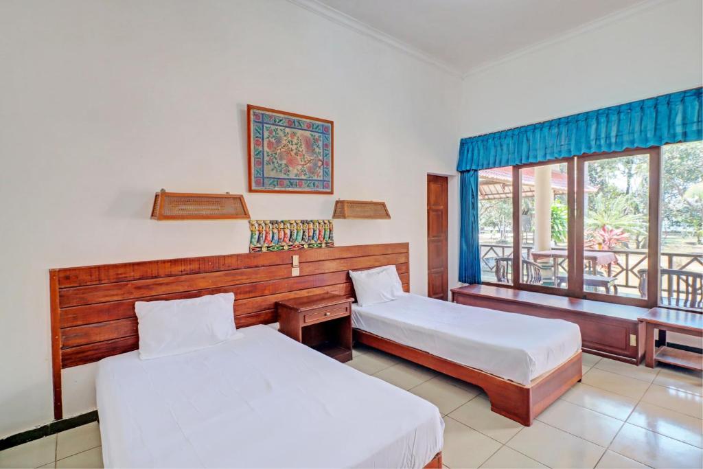 a hotel room with two beds and a balcony at Capital O 93236 Hotel Hapel Negara in Banyubiru