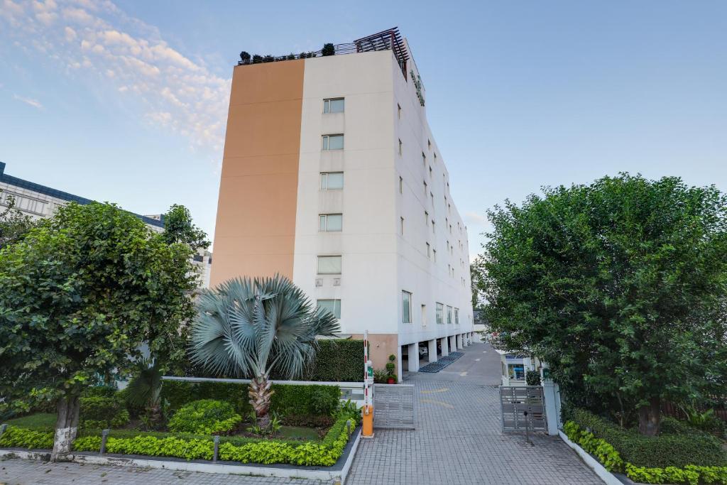 um edifício branco com uma palmeira em frente em Lemon Tree Hotel Chandigarh em Chandīgarh