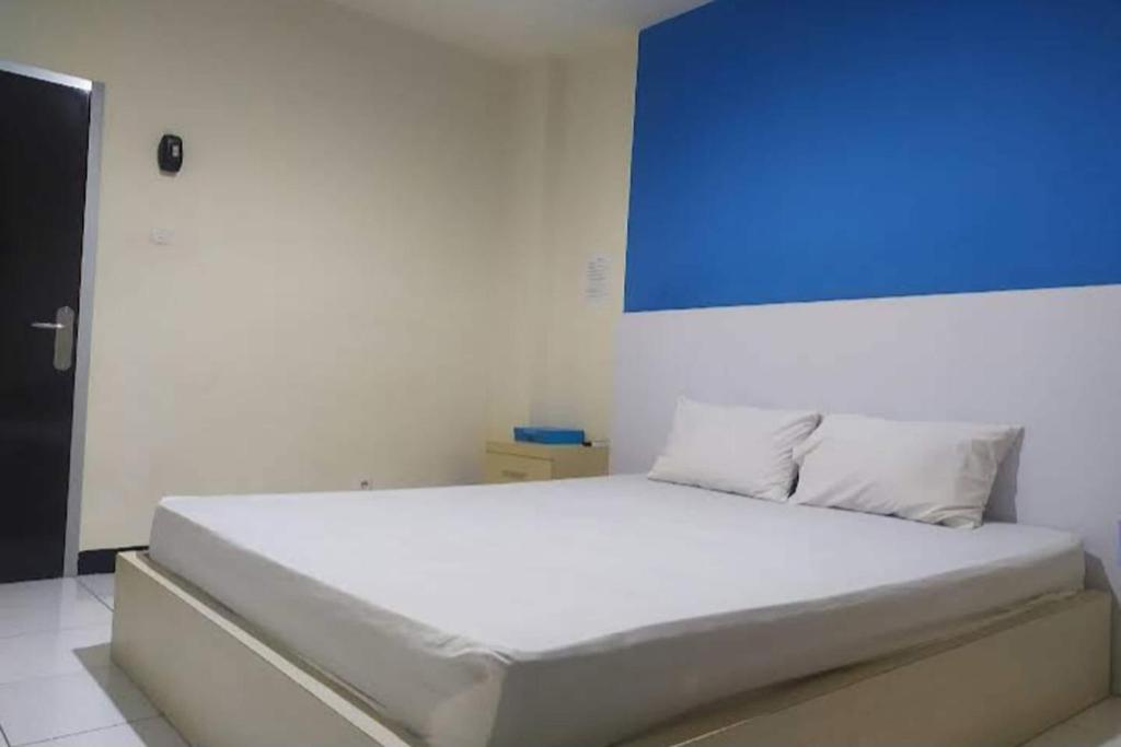 una camera da letto con un letto bianco con una lavagna blu sul muro di OYO 93246 Kanditha Homestay a Montongbuwoh