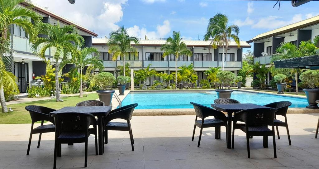 ein Hotel mit Tischen und Stühlen neben einem Pool in der Unterkunft Bohol Jewel Resort in Dauis