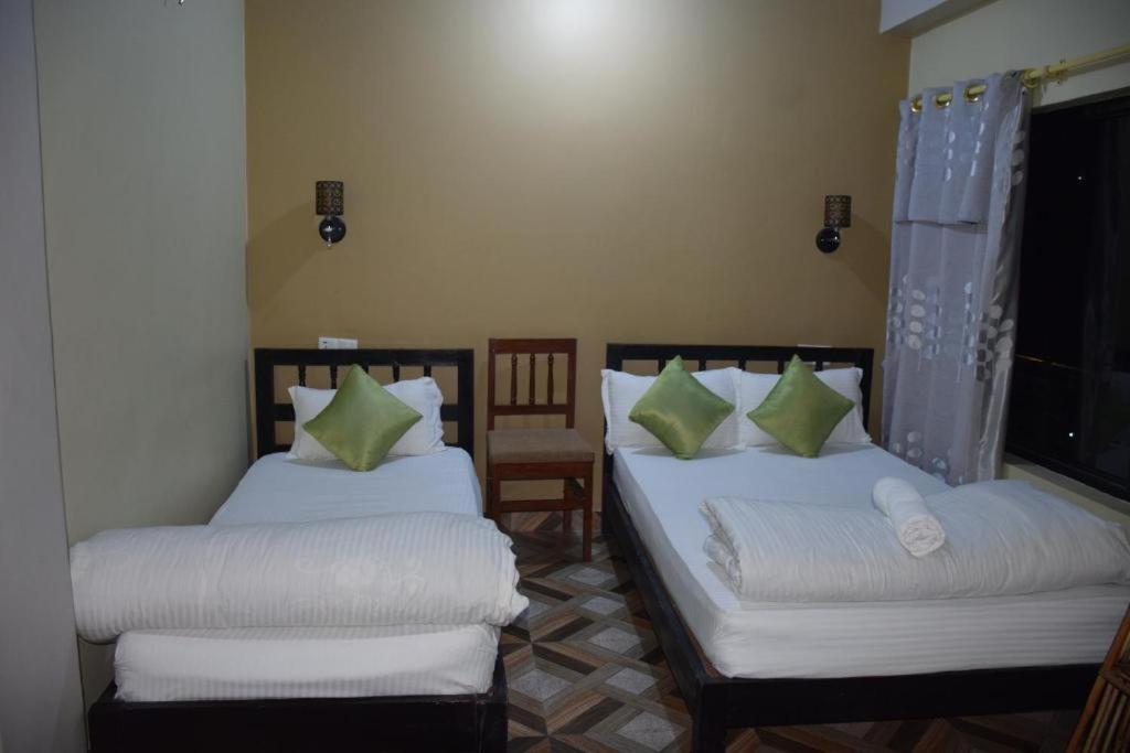 two twin beds in a room with a window at Hotel Garangja in Bandipur