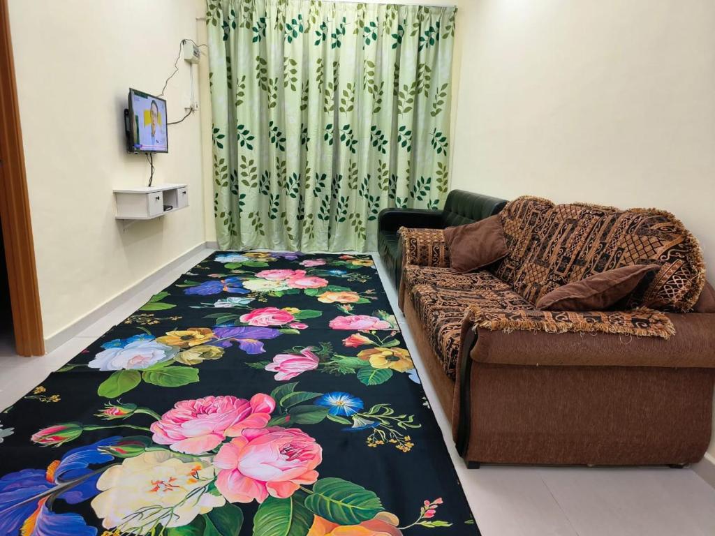 a living room with a couch and a flower carpet at Wafiy Homestay in Machang