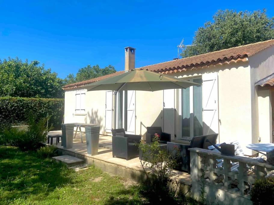 a patio with an umbrella and a table at Charmante Maison au pied du Luberon in Cheval-Blanc