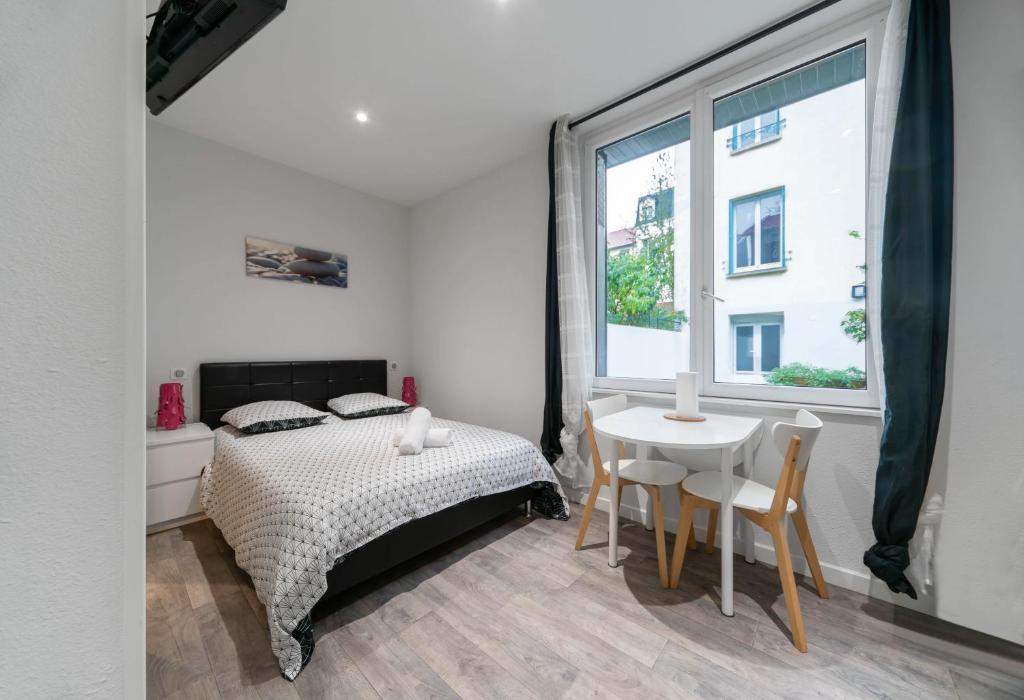 1 dormitorio con cama, mesa y ventana en Residence Germot - Appartements design Centre Ville proche Thermes, en Vichy