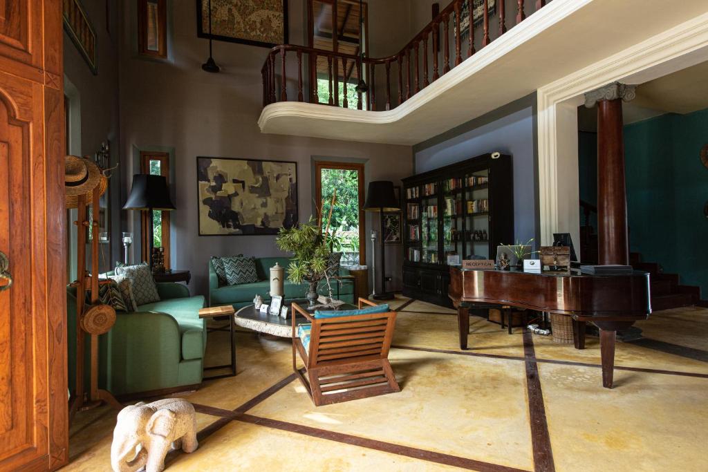 a living room with a piano and a green couch at Eraeliya Villas & Gardens in Weligama