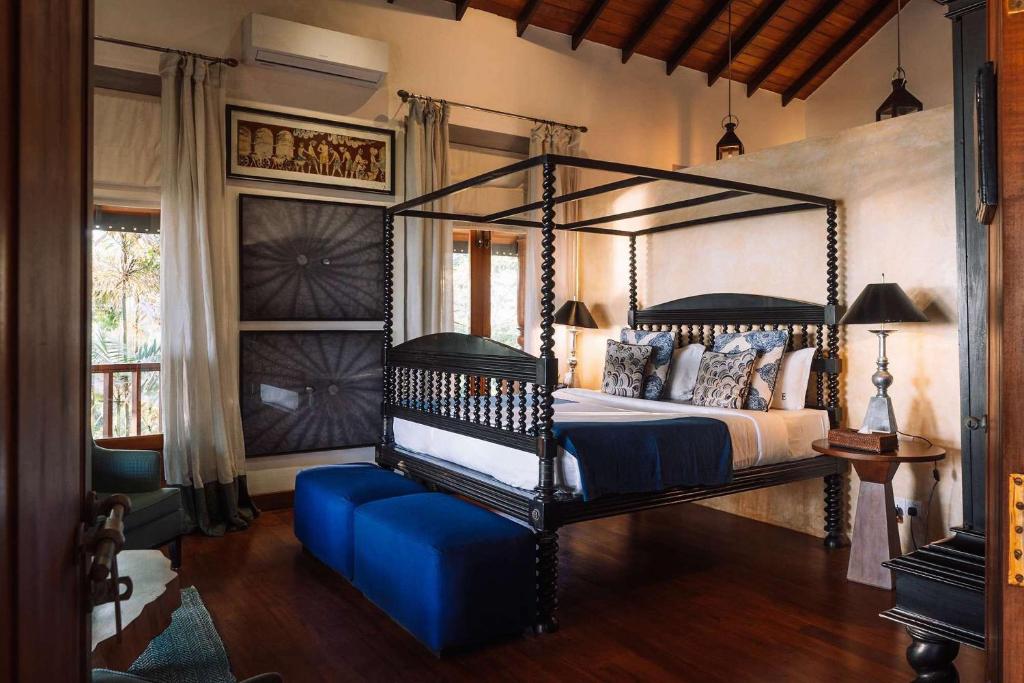 a bedroom with a canopy bed and a blue ottoman at Eraeliya Villas & Gardens in Weligama