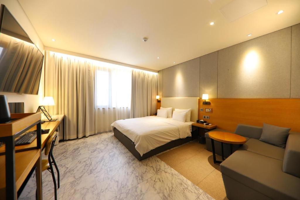 um quarto de hotel com uma cama e um sofá em Brooks Business em Changwon