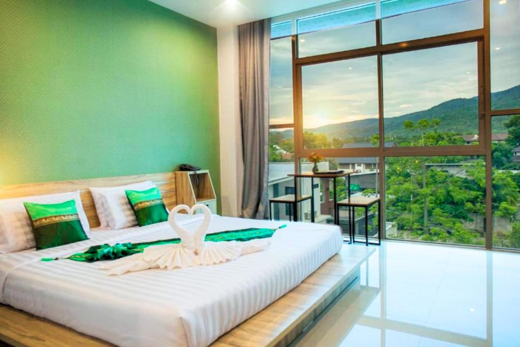 a bedroom with a large bed with a large window at Km Hotel Chiang Mai in Chiang Mai